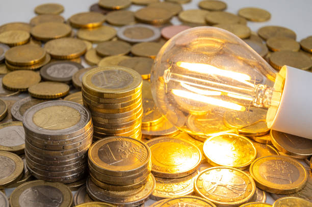 istock Light bulb turned on, with coins around. Energy costs. 1995303332
