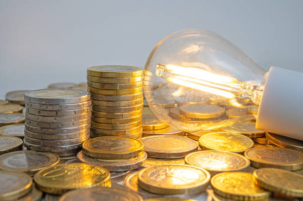 istock Light bulb turned on, with coins around. Energy costs. 1995303337