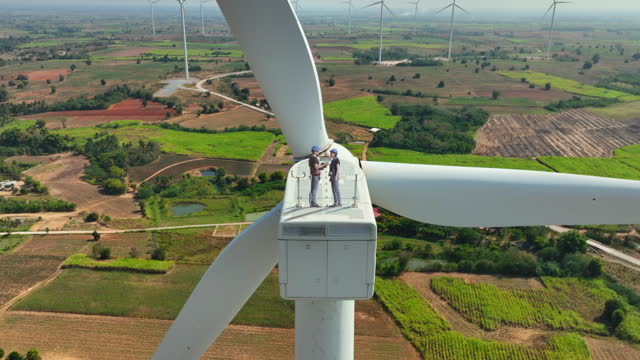 cuacasian man and woman electric engineer discussing for maintenance wind turbine or windmill on the top of wind turbine.Sustainable,renewable,clean energy concept.aerial  top view.