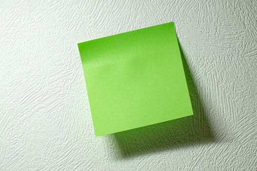 Empty paper sticker on white wall. Space for your text.