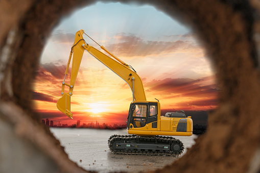 Crawler excavator are digging soil in the tunnel construction site. With a sunrise background  of city