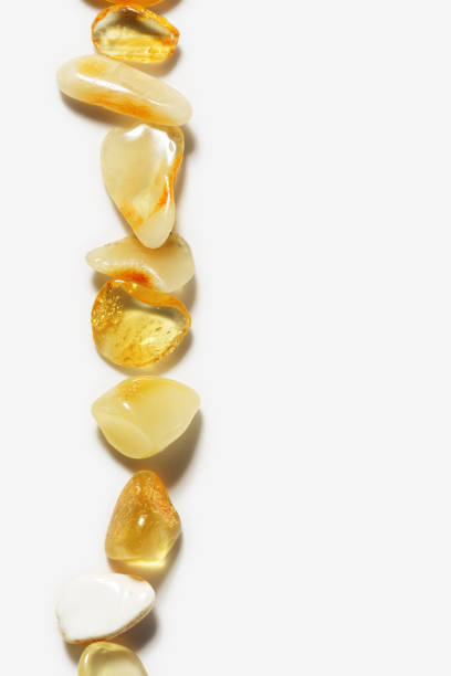 Natural gemstone amber texture background, light stones yellow ivory white colors with beautiful shadows and sunlight. Top view Amber texture, vertical photo with copy space. Aesthetic sunstones row