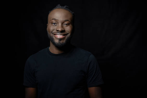 Young African man smiling at camera on black background