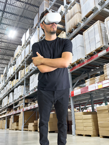 Young man wearing a Virtual Reality headset in a warehouse