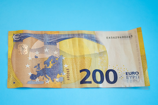 two hundred euro banknote 200 on blue background from above slightly wavy