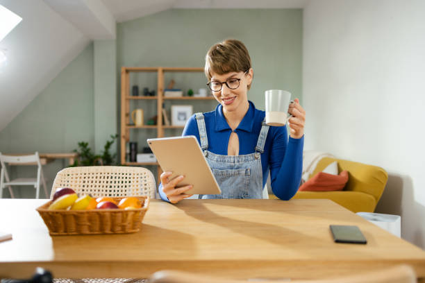 istock Young woman enjoying coffee and using tablet 1995414747