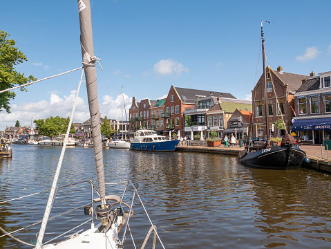 Sailboat motoring in Het Dok canal near Kortestreek quay in old town of Lemmer, Friesland, Netherlands