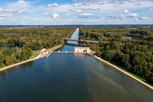 A summer landscape with a lake, canal forests, hydroelectric power plant, highway and blue sky, aerial view.
