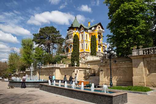 Kislovodsk, Russia - May 09, 2022: Fountains and pedestrian area on Lenin Avenue. A beautiful old mansion - Kshesinskayaâs Dacha or Tvalchrelidzeâs Estate