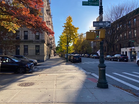 New York, NY USA - November 14, 2023 : Afternoon sunlight on a sidewalk on the corner of Manhattan Avenue and W 123rd Street aka Fannie Pennington Way in a historic residential neighborhood in Harlem, New York City