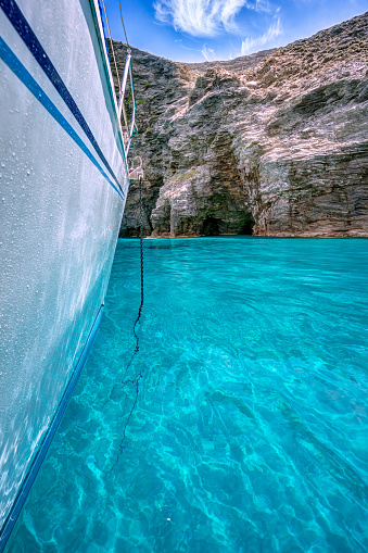Sailing yacht anchored at a cliffy beach with transparent turquoise waters, in Gyaros island, Greece
