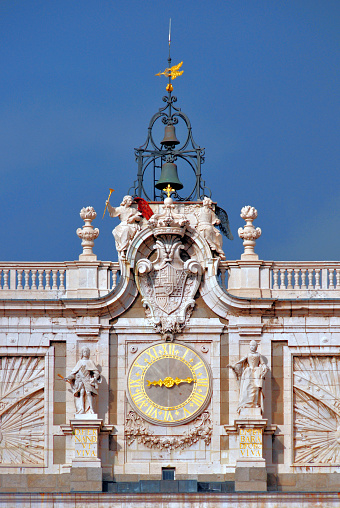 Madrid, Spain: Royal Palace / Palacio Real - south façade detail - clock, bells, weather vane and Bourbon dynasty coat of arms - detail of the entablature on south façade, facing Plaza de la Armería.