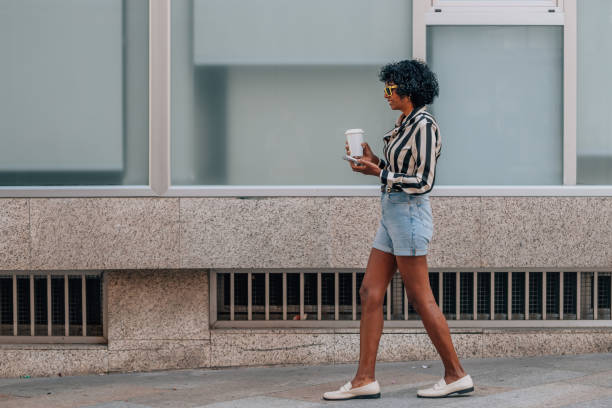 istock woman walking with mobile phone and cup 1995529622