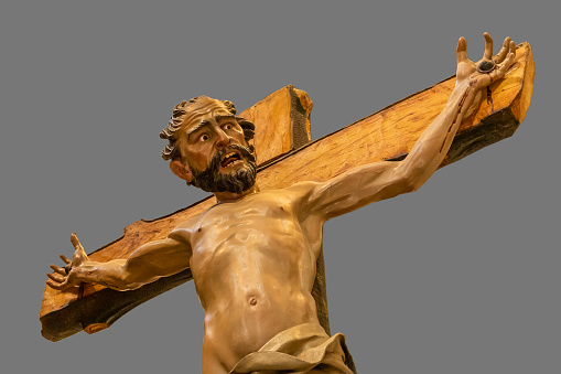 Polychrome wood carving of a thief crucified next to Christ.