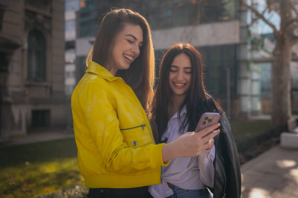 istock Two beautiful young women using phone in the city 1995556402