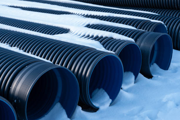 Plastic black corrugated drainage pipes are neatly arranged on the snowy surface during the winter.