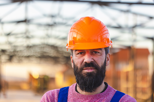 A powerful portrait of a male construction worker, his expression conveying both strength and focus as he takes a moment.