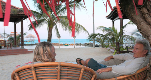Mature couple relax under tree decorated for Chinese New Years on beach