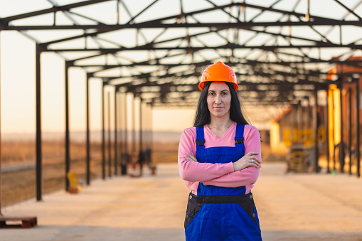 In this image, a female laborer poses for a portrait, showcasing her strength and resilience amidst the construction environment.