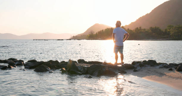 istock Mature man explores beach at sunrise 1995599476