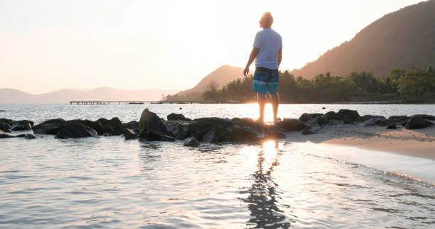 istock Mature man explores beach at sunrise 1995599996
