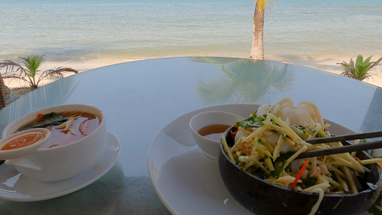 POV of soup and salad on table on beach above sea
