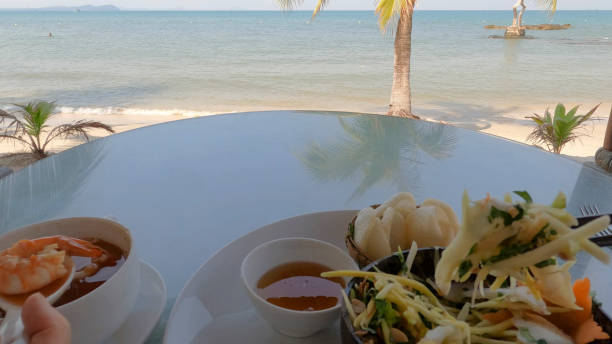 POV of soup and salad on table on beach above sea