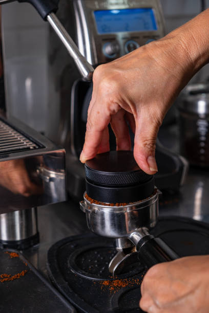 istock woman's hands pressing roasted and ground coffee to use in coffee maker 1995634489
