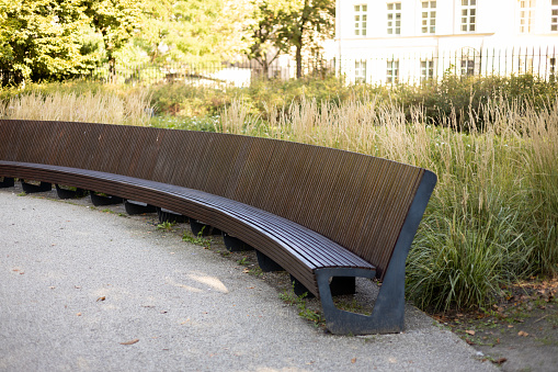 City park with Wood modern Park Bench. Geometry on nature and place to rest. Furniture in garden.
