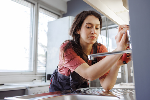 A young woman fixing a faucet - Home Improvement concepts