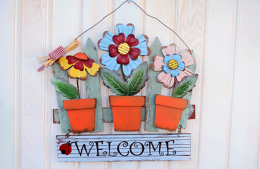 Wood welcome sign with flowers  hanging on a door