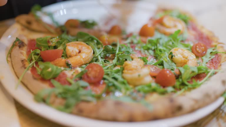 Teenager enjoying eating shrimp pizza in a restaurant.