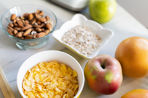 Healthy ingredients for tasty breakfast. Cereal, oatmeal, apple, almonds, pineapple, grapefruit.