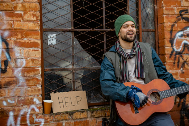 istock Man Beggar Playing Guitar on the Street 1995703308