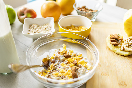 Healthy ingredients for tasty breakfast. Pineapple, cereal, oatmeal, corn flakes, grapefruit, apple and milk.