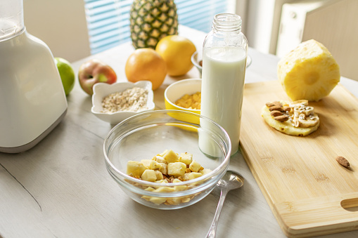 Healthy ingredients for tasty breakfast. Pineapple, cereal, oatmeal, corn flakes, grapefruit, apple and milk.