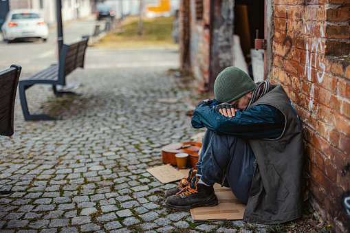 Poor tired stressed depressed elderly Asian woman homeless sitting on the street in the shadow of the building and begging for help and money, Elderly Asian woman abandoned concept