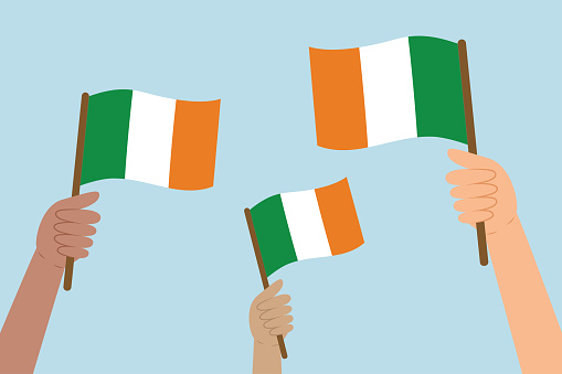 Diverse hands raising flags of Ireland. Vector illustration of Irish flags in flat style on blue background.