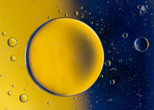 Abstract macro with oil drops in water, looking like planets in space.