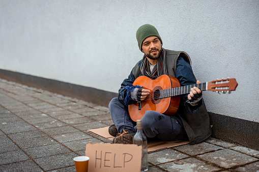 Man Beggar Living in Poverty Playing the Guitar to Sing a Song and Ask for Money on the Street. Social Problems of Modern Society. Lifestyle of Tramp, Living in the Streets.