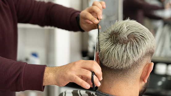 Close-up Barber man using comb and scissors