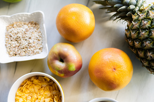 Healthy ingredients for tasty breakfast. Pineapple, cereal, grapefruit, apple.