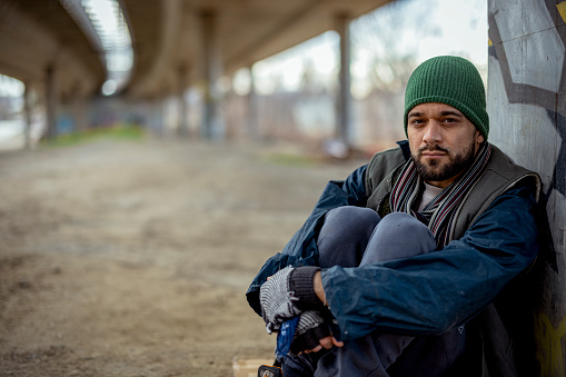 Portrait of a handsome young man standing outdoors on city street. Male wearing jacket and knitted hat standing outside on winter day.