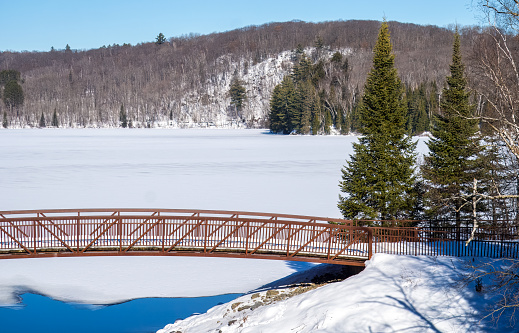Iconic footbridge over frozen and snow covered Arrowhead Lake, which is a ski trail in winter.