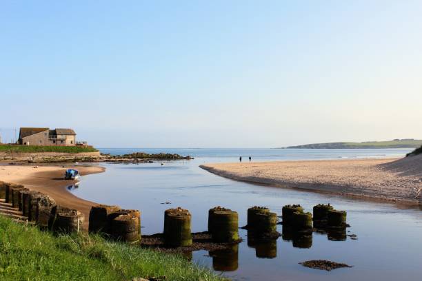 an incredibly scenic view of the small scottish seaside town of cruden bay, on a beautiful summer day in the highlands of scotland.  the ocean is calm and a house is in the background along the shore. - cruden bay стоковые фото и изображения