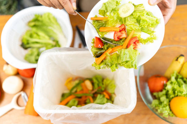 istock Ecology compost supply Kitchen waste recycling composter environmentally friendly. The young man throws leftover fruit peel egg shell and vegetables reduce waste 1995807561