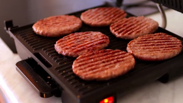 hamburger patties on an electric grill. There is a grill in the kitchen
