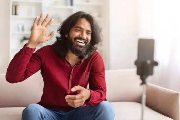 Photo of Positive young indian man blogger streaming from home