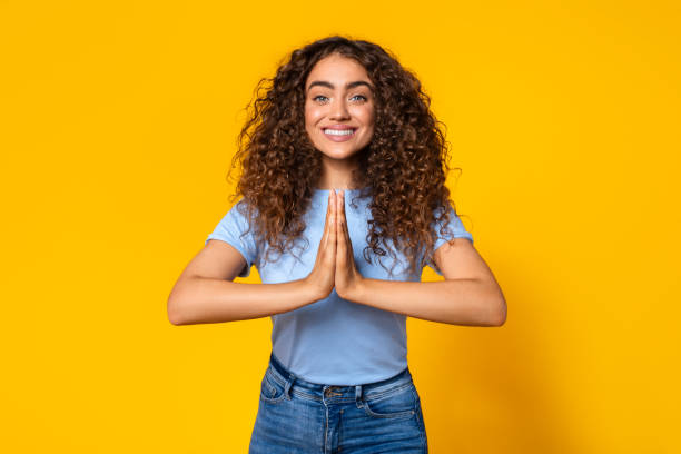 istock Grateful woman with hands in prayer pose on yellow background 1995838175