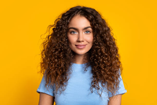 istock Confident curly-haired woman smiling on yellow 1995838184